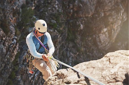 simsearch:649-05949892,k - Male rock climber rappelling, descending from rope Photographie de stock - Premium Libres de Droits, Code: 6113-09131743