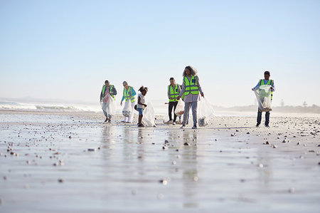 Volunteers cleaning up litter on sunny wet sand beach Stock Photo - Premium Royalty-Free, Code: 6113-09240240