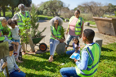 Man with digital tablet leading volunteers planting trees in sunny park Photographie de stock - Premium Libres de Droits, Code: 6113-09240236