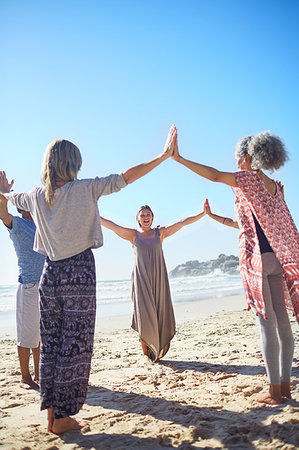 Group joining hands in circle on sunny beach during yoga retreat Stock Photo - Premium Royalty-Free, Code: 6113-09240607