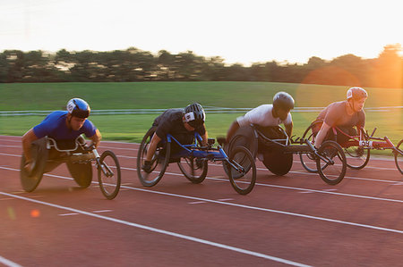 simsearch:6113-07588752,k - Paraplegic athletes speeding along sports track in wheelchair race Photographie de stock - Premium Libres de Droits, Code: 6113-09240638
