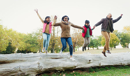 simsearch:6113-06909382,k - Happy, playful family holding hands, jumping off log in autumn park Stock Photo - Premium Royalty-Free, Code: 6113-09240966
