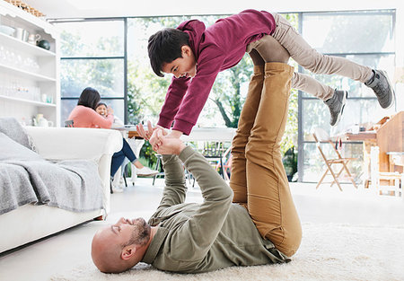 Father lifting son with legs on living room floor Stock Photo - Premium Royalty-Free, Code: 6113-09241021