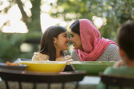 Affectionate mother in hijab rubbing noses at dinner table Stock Photo - Premium Royalty-Free, Code: 6113-09241028