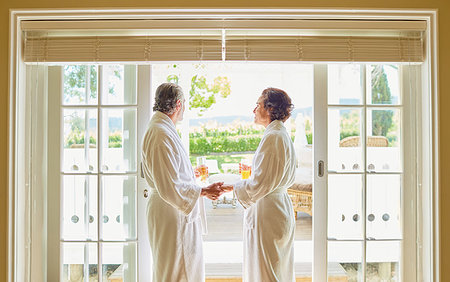 simsearch:6113-07242393,k - Mature couple in spa bathrobes drinking mimosas at hotel patio door Stock Photo - Premium Royalty-Free, Code: 6113-09241193