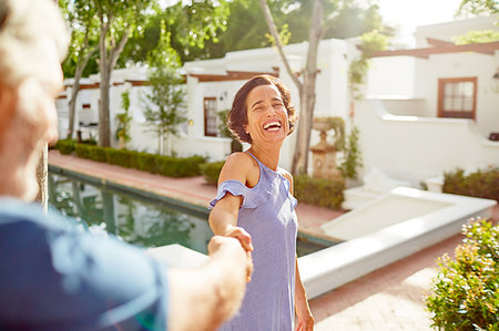 simsearch:6113-07242393,k - Happy, carefree mature couple holding hands at sunny resort poolside Stock Photo - Premium Royalty-Free, Code: 6113-09241231