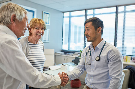 Male doctor shaking hands with senior couple in clinic doctors office Photographie de stock - Premium Libres de Droits, Code: 6113-09241571