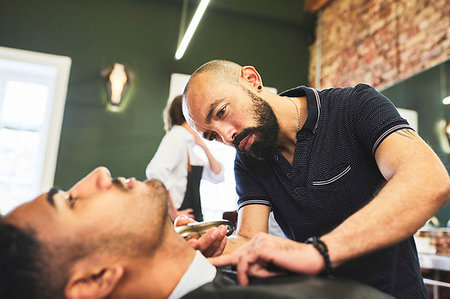 Focused male barber giving customer a shave in barbershop Stock Photo - Premium Royalty-Free, Code: 6113-09272567