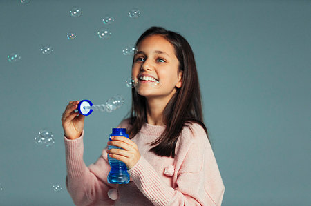 simsearch:695-03376367,k - Happy, playful girl with bubble wand blowing bubbles Stock Photo - Premium Royalty-Free, Code: 6113-09272516