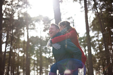 simsearch:6108-06166561,k - Happy, playful couple piggybacking in sunny woods Foto de stock - Sin royalties Premium, Código: 6113-09272522
