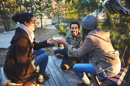 Happy friends drinking wine at campsite in woods Stock Photo - Premium Royalty-Free, Code: 6113-09272795