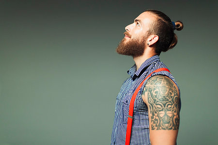 simsearch:6113-06909277,k - Curious hipster man with beard and shoulder tattoo looking up Stock Photo - Premium Royalty-Free, Code: 6113-09200037