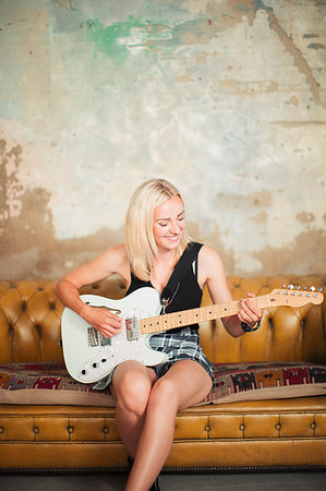 simsearch:614-06719795,k - Young woman playing electric guitar on sofa Stock Photo - Premium Royalty-Free, Code: 6113-09220588