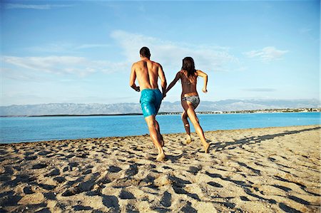 Young couple running into water Stock Photo - Premium Royalty-Free, Code: 6115-06732807