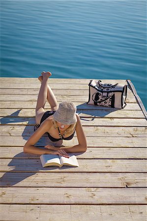 Croatia, Young woman with straw hat reads book on boardwalk, by the sea Stock Photo - Premium Royalty-Free, Code: 6115-06732970