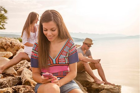 Croatia, Dalmatia, Young people at the seaside, using phones Stock Photo - Premium Royalty-Free, Code: 6115-06733081