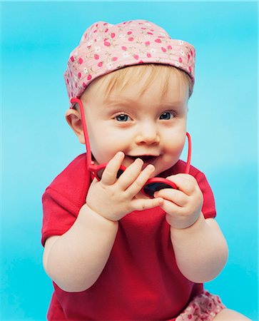 Baby Girl Holding Sunglasses In Hands, Munich, Bavaria, Germany, Europe Stock Photo - Premium Royalty-Free, Code: 6115-07539732