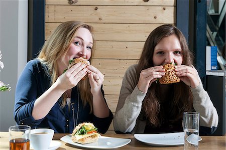 simsearch:6115-07282765,k - Two young women eating sandwiches in a cafe Stock Photo - Premium Royalty-Free, Code: 6115-08100523