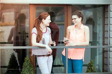 flat - Two young women having a drink on balcony, Munich, Bavaria, Germany Foto de stock - Sin royalties Premium, Código: 6115-08100745