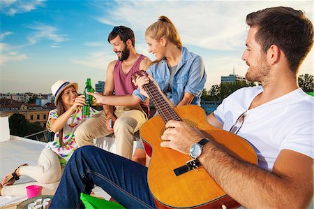 Young people listening to guitar music at rooftop party Stock Photo - Premium Royalty-Free, Code: 6115-08101150