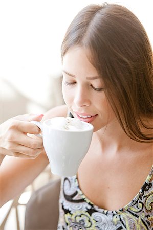 Young woman with brown hair having a cappuccino Stock Photo - Premium Royalty-Free, Code: 6115-08101137