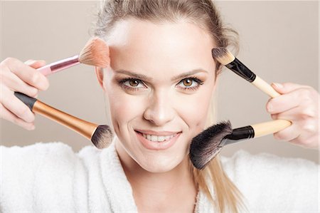 simsearch:693-06022101,k - Young woman holding makeup brushes Stock Photo - Premium Royalty-Free, Code: 6115-08105086