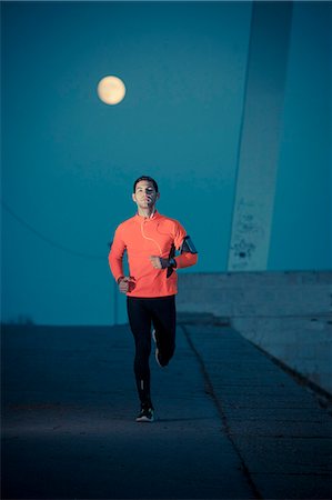 Male runner jogging against full moon Stock Photo - Premium Royalty-Free, Code: 6115-08105027