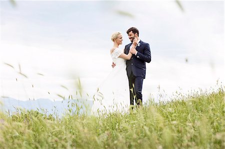 Bride and groom embracing in meadow Stock Photo - Premium Royalty-Free, Code: 6115-08239379