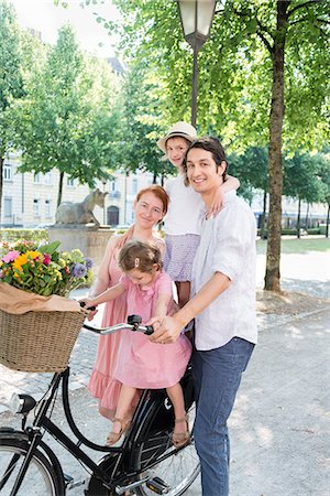 person in a basket of a bike - Family with two children pushing bicycle in city Stock Photo - Premium Royalty-Free, Code: 6115-08416134