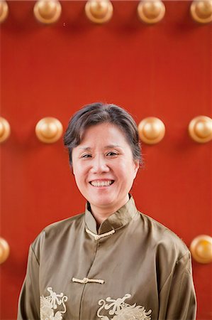 Mature woman in traditional clothes standing next to traditional Chinese door Photographie de stock - Premium Libres de Droits, Code: 6116-06939047