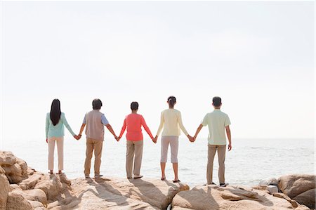 simsearch:6116-06939008,k - Multi-generational family holding hands on rocks by the sea, rear view Stock Photo - Premium Royalty-Free, Code: 6116-06939007