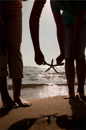 sea starfish pictures - Silhouette of mother and daughter picking up a starfish on the beach Stock Photo - Premium Royalty-Free, Code: 6116-06939017