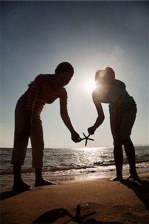 sea starfish pictures - Silhouette of mother and daughter holding a starfish on the beach Stock Photo - Premium Royalty-Free, Code: 6116-06939018