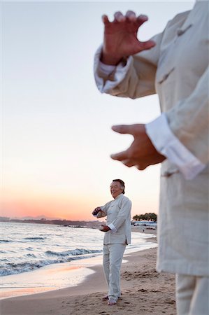 simsearch:693-05552857,k - Two older people practicing Taijiquan on the beach at sunset, close up on hands Stock Photo - Premium Royalty-Free, Code: 6116-06939032