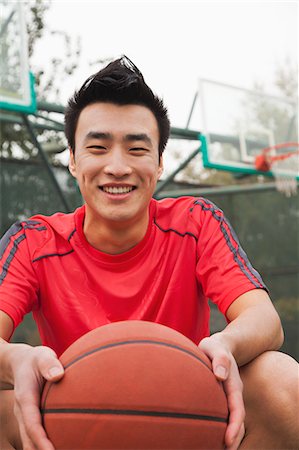 Young man sitting with a basketball on the basketball court, portrait Stock Photo - Premium Royalty-Free, Code: 6116-06939327