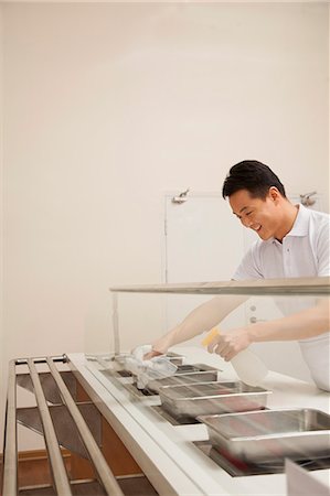 Cafeteria worker cleaning food serving area Photographie de stock - Premium Libres de Droits, Code: 6116-06939481