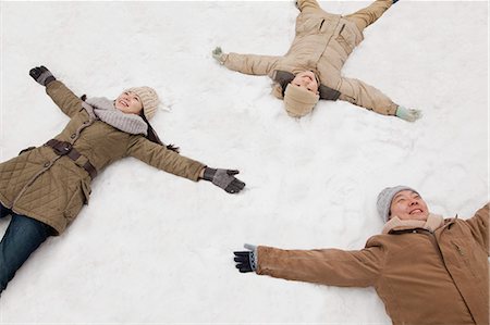 Family laying in snow making snow angels Stock Photo - Premium Royalty-Free, Code: 6116-06939547