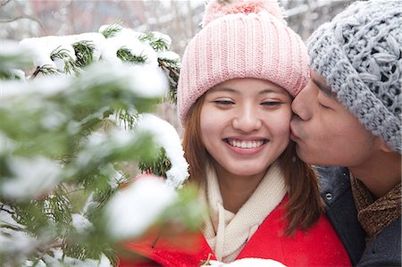 Young man kissing young woman in park in snow Stock Photo - Premium Royalty-Free, Code: 6116-06939534