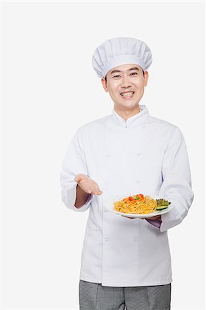 Chef showing prepared food, studio shot Stock Photo - Premium Royalty-Free, Code: 6116-07084905