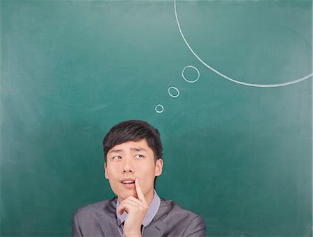 Young man with thought bubble on blackboard Stock Photo - Premium Royalty-Free, Code: 6116-07085307