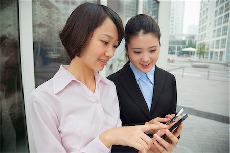 simsearch:614-06896117,k - Young businesswomen looking at their cell phones Stock Photo - Premium Royalty-Free, Code: 6116-07085566