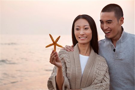 sea starfish pictures - Young Couple Looking At a Seashell Stock Photo - Premium Royalty-Free, Code: 6116-07085987