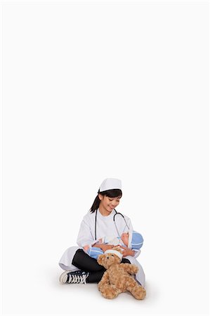 preteen girl with doctor - Girl dressed up as doctor with teddy bear and doll Stock Photo - Premium Royalty-Free, Code: 6116-07086279