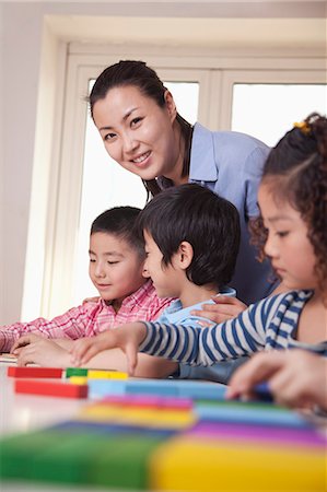 Teacher Helping Her Students and Looking at Camera Stock Photo - Premium Royalty-Free, Code: 6116-07235595