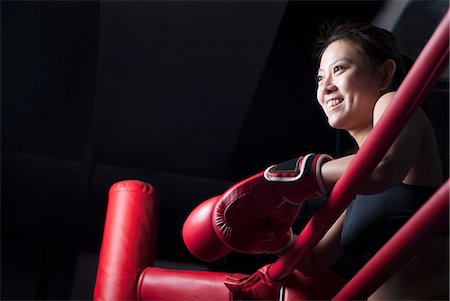 female boxing - Smiling female boxer resting her elbows on the ring side, looking away, low angle view Stock Photo - Premium Royalty-Free, Code: 6116-07235770