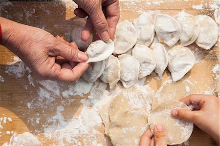 Senior woman and girl making dumplings, hands only Stock Photo - Premium Royalty-Free, Code: 6116-07235723