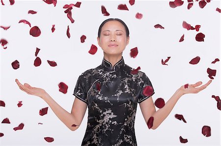 petal - Woman in traditional clothing and arms outstretched with rose petals coming down around her in mid air, studio shot Stock Photo - Premium Royalty-Free, Code: 6116-07235861