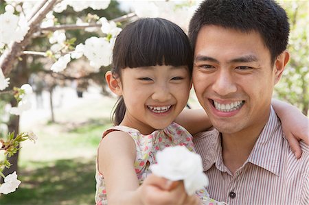 simsearch:6116-07236315,k - Smiling father and daughter enjoying the cherry blossoms on the tree in the park in springtime, daughter holding a flower Foto de stock - Sin royalties Premium, Código: 6116-07235873