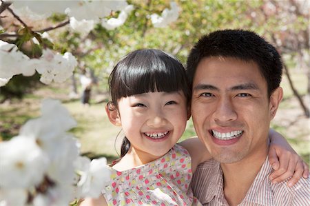 simsearch:6116-07236315,k - Smiling father and daughter enjoying the cherry blossoms on the tree in the park in springtime, portrait Foto de stock - Sin royalties Premium, Código: 6116-07235872