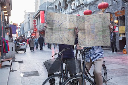 Young man and woman on bicycles holding maps. Stock Photo - Premium Royalty-Free, Code: 6116-07235812